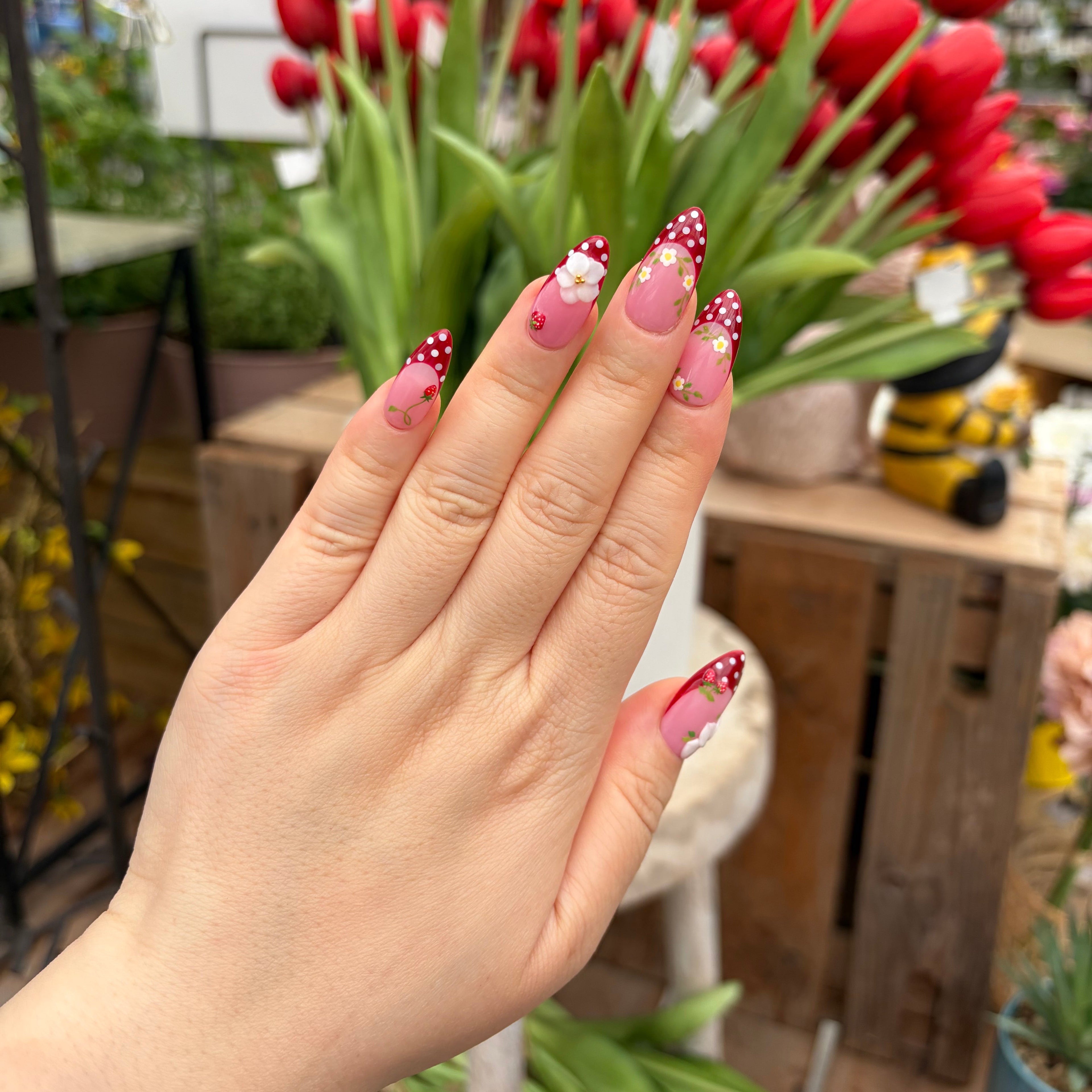 Vibrant handmade press-on nails from the Bloom & Glory collection featuring 3D white garden flowers, strawberry red polka dots