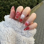 Close-up of a hand with strawberry-themed nail art with ribbon and lace