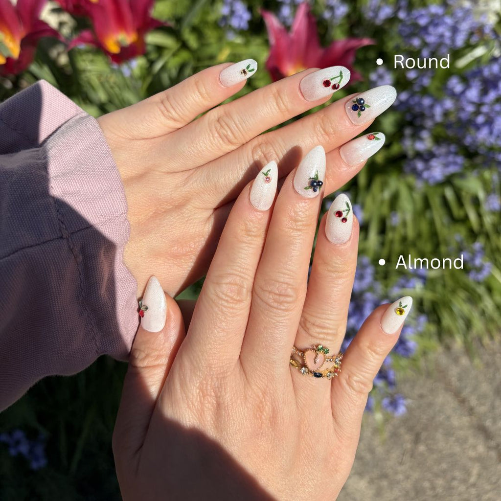 press-on nails feature delicate hand-painted cherries and blueberries, finished with brilliant authentic Swarovski charms on a shimmering white glitter base. Perfect for a dainty, premium, and summer-ready look.