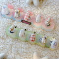 Set of decorative press-on nail tips handmade with 3D cartoon character puppy designs on a textured milky color surface. floral designs for spring