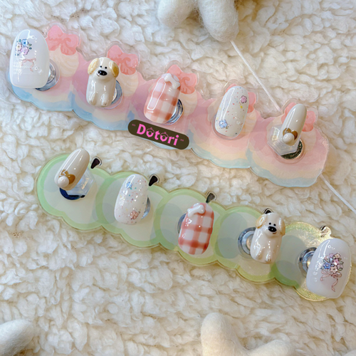 Set of decorative press-on nail tips handmade with 3D cartoon character puppy designs on a textured milky color surface. floral designs for spring