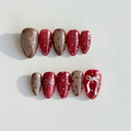 Handmade press-on nails in alternating ruby red and champagne glitter with white bows and polka dot accents.