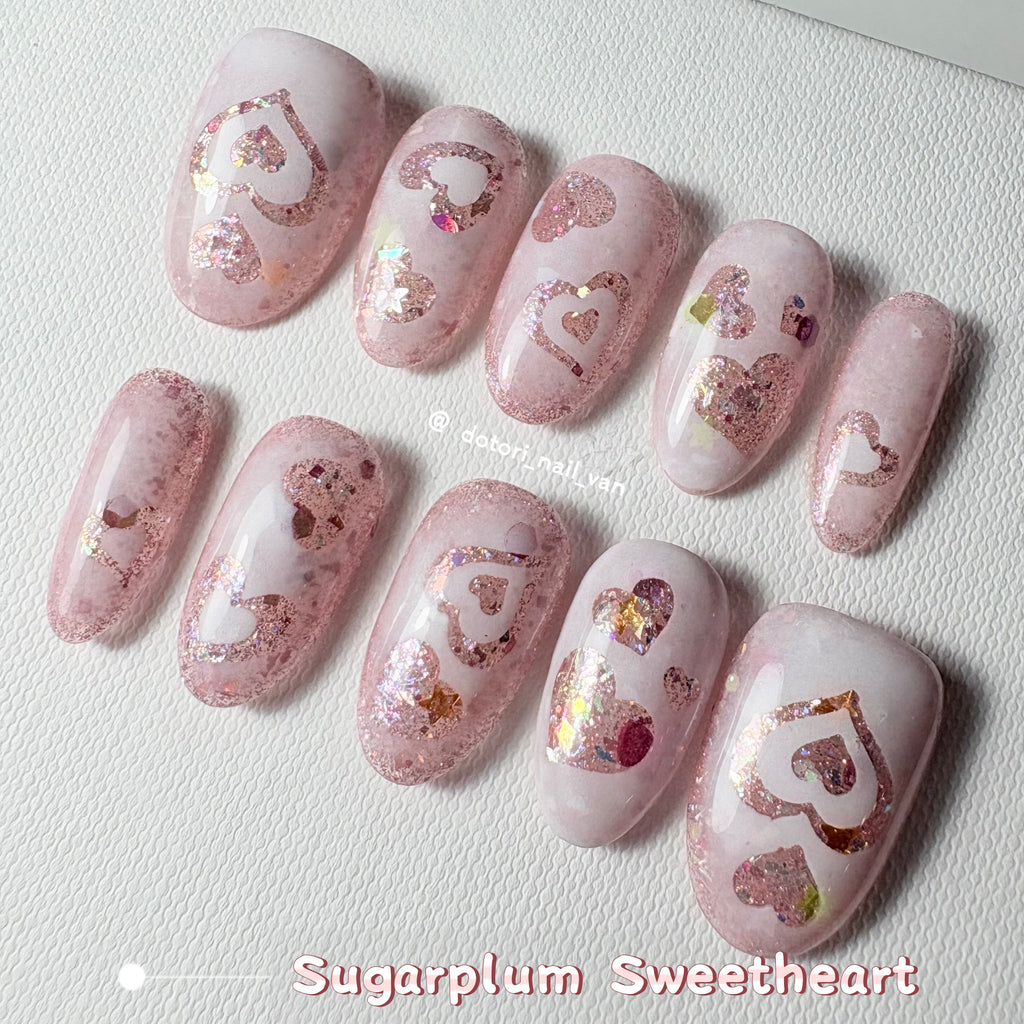 Close-up of holographic heart nail art shimmering in the light.