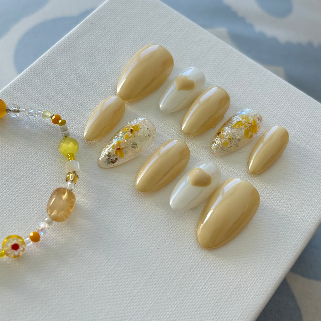 Handmade butter-yellow press-on nails with delicate dry floral designs and silver chrome tips