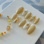 Handmade butter-yellow press-on nails with delicate dry floral designs and silver chrome tips