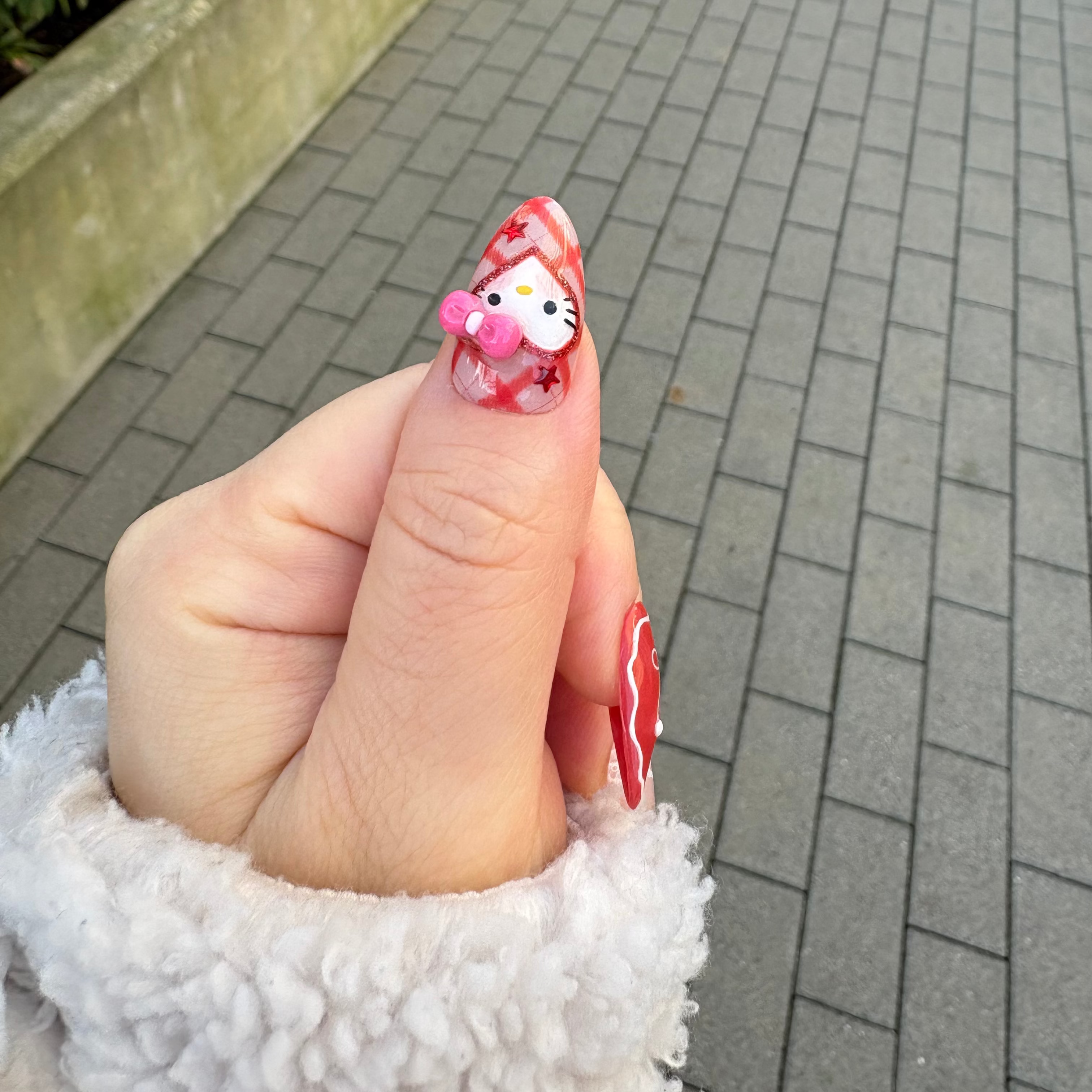 press-on Nail art of Hello Kitty with 3d pink ribbon on a model fingerss