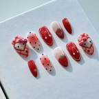 Handmade red and white press-on nails featuring gingham patterns, strawberries, and a cute Hello Kitty character.