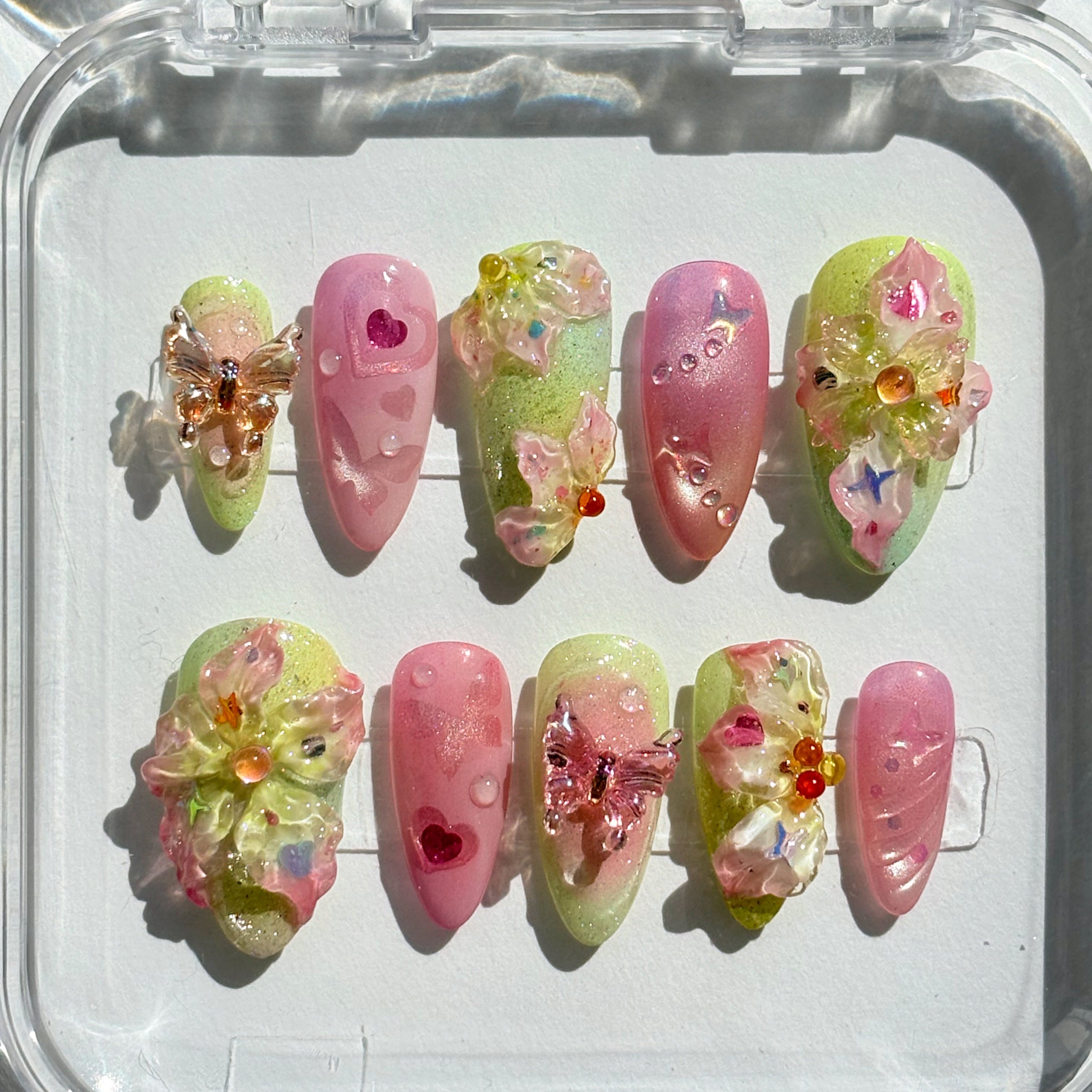 Close-up of the intricate green vine artwork and 3D textured flowers on a soft yellow spring press-on nail.