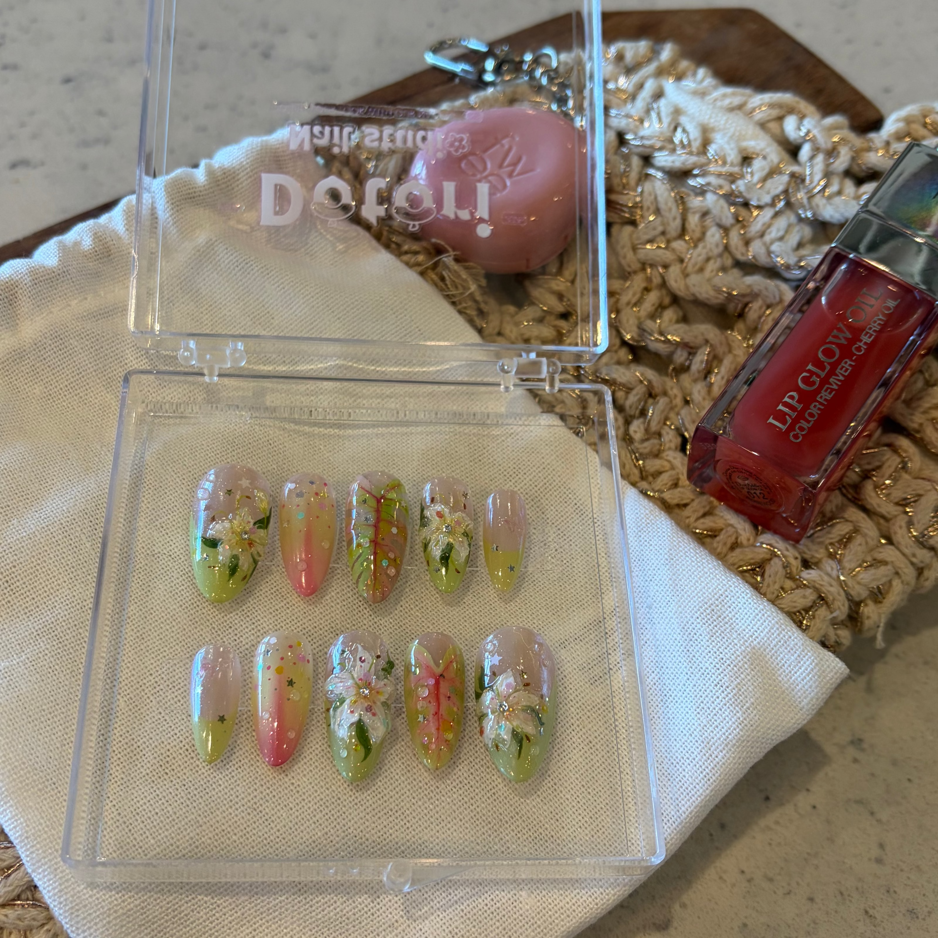 Handmade botanical press-on nails with 3D white lilies, hand-painted green leaves with pink veins, and 3D dewdrop accents.