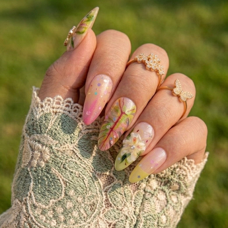 Close-up of the intricate pink leaf veins and shimmering gold star details on a sage green tropical-themed nail.