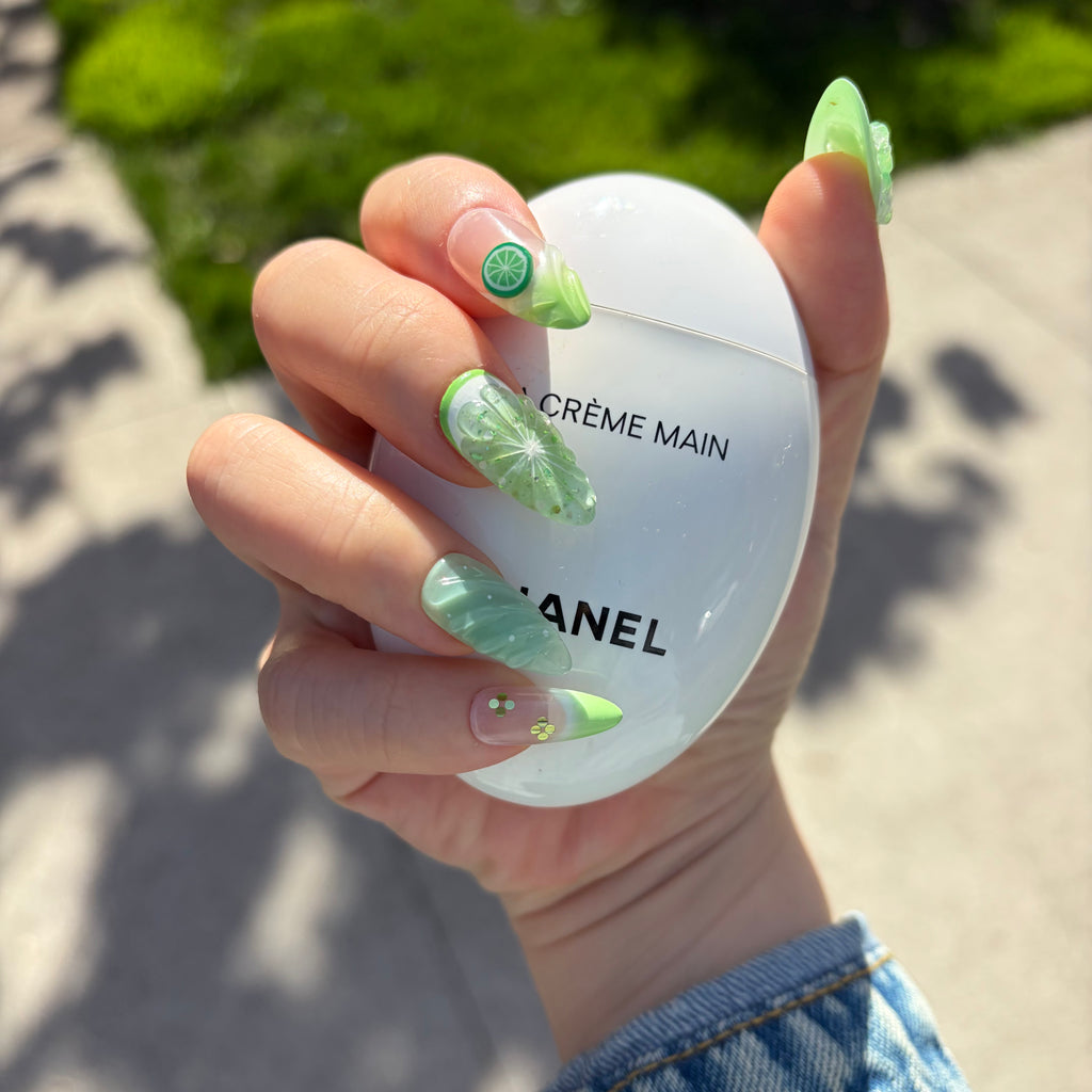 Close-up of the realistic citrus fruit slice charms and 3D sculpted floral details on a vibrant summer nail set.