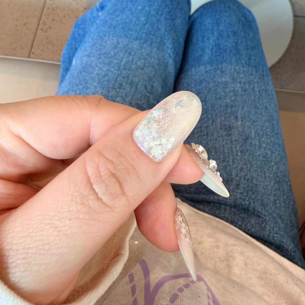 Discover "Starlight Serenade"—luxury press-on nails featuring genuine Swarovski crystal accents and iridescent star glitters on a soft milky-nude base. These reusable, salon-quality bling sets offer an ethereal, galaxy-inspired look for any special occasion.