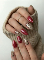 Hand model wearing Champagne & Crimson Couture nails with a cozy beige sweater and gold ring, showcasing a festive, elegant manicure.