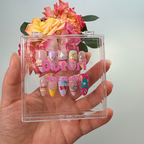 Handmade Y2K collection press-on nails featuring 3D fruit and flower charms, colorful rainbow stripes, teal stars, and crystal rhinestone designs on a multi-colored pastel