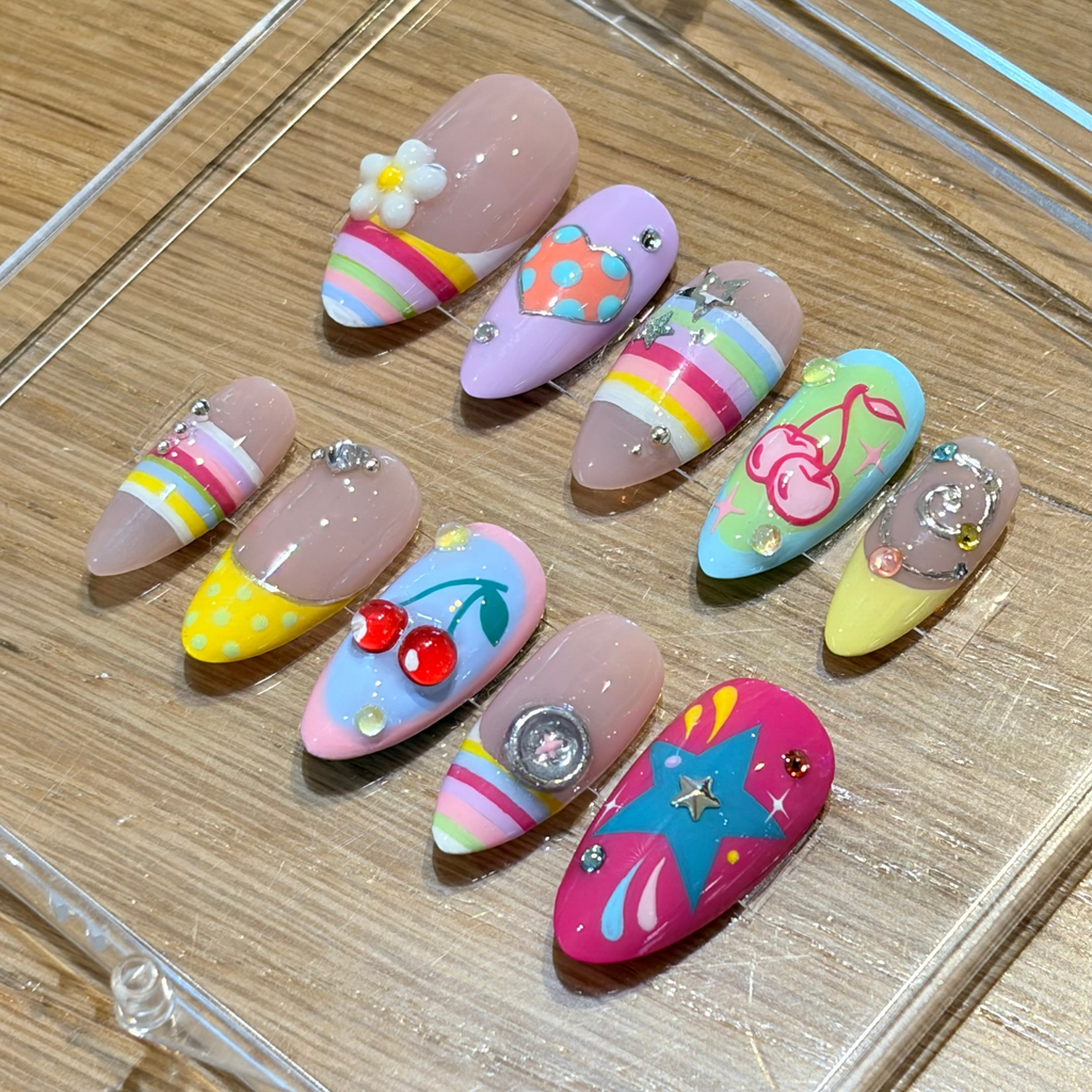 Level up your look with "Sugar Rush" from our Y2K Collection. Featuring a mismatched explosion of 3D cherry charms, hand-sculpted white flowers, rainbow candy stripes, and silver star rhinestones, these handmade luxury press-on nails deliver pure early-2000s main character energy.